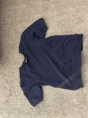 Mörkblå t-shirt med puffärm - En stilren mörkblå t-shirt med korta puffärmar och rund hals. T-shirten har ribbad kant nertill och är tillverkad i mjuk bomull, perfekt för en avslappnad look.