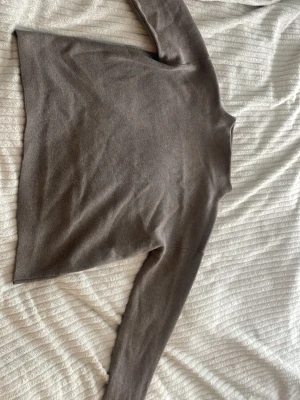 Beige fin stickad tröja med hög krage - Mysig beige/brun stickad tröja med hög krage och långa ärmar. Tröjan har en rak passform och ribbstickade muddar vid ärmsluten. Perfekt för lager-på-lager och enkel att matcha med jeans eller kjol.