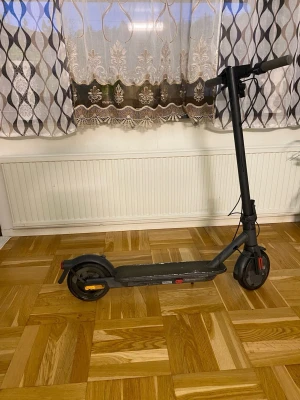Svart elscooter med LED-bakljus - Säljer en svart elscooter med LED-bakljus och robust ram i metall. Scootern har bred fotplatta med halkskydd, stora hjul och handtag i gummi. Perfekt för smidig transport i stan eller till skolan.