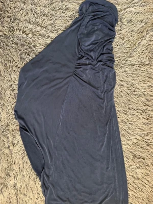 Blå långklänning i sammet - Snygg blå långklänning i mjuk sammet med rynkade detaljer upptill. Klänningen har en elegant och stilren look, perfekt för dig som gillar en klassisk men trendig stil.