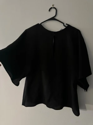 Svart blus - Jättesnygg svart blus köpt i Frankrike!! Den går in lite i midjan och har flowiga armar! suuupersnygg nu till sommaren!😍