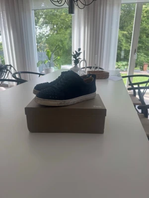 Svarta Louboutin sneakers med nitar - Snygga mörkblå sneakers från Christian Louboutin med coola nitar på ovandelen och den klassiska röda sulan. . Perfekta för dig som vill sticka ut med din stil. Men de saknas några spikar o de går och beställa. Säljer dessa för jag tröttnat på skorna. Hör gärna av er för minsta fundering. Priset går och prata om 
