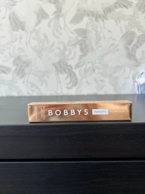 Bobbys Flyaway Hair Stick - Bobbys Flyaway Hair Stick är en smidig hårprodukt i en guldig förpackning som hjälper till att tämja småhår och ge en slät finish. Perfekt för att fixa babyhairs och hålla frisyren på plats. Enkel att använda och passar alla hårtyper. Säljer då den inte kommer till användning. Oöppnad och oanvänd.