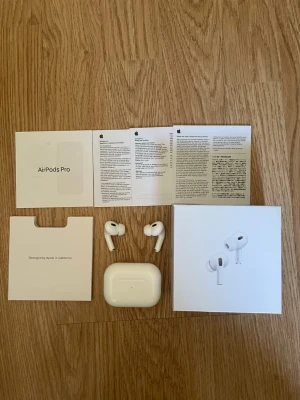 Apple AirPods Pro trådlösa hörlurar - Säljer ett par vita Apple AirPods Pro med laddningsetui och originalförpackning. Hörlurarna har en stilren design i plast och levereras med manualer och tillbehör. Perfekta för dig som vill ha brusreducering och grymt ljud i ett kompakt format.