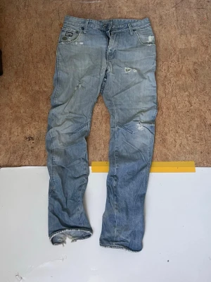Ljusblå vintage G-Star jeans  - Ljusblå jeans från G-Star med slitna detaljer och råa kanter. Modellen har klassisk femficksdesign, dragkedjegylf. Vintage och i bra skick 