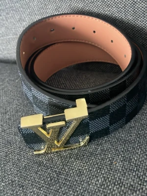 Zara bälte - Snyggt bälte från Zara  med klassiskt rutigt mönster i svart och grått. Bältet har ett ikoniskt spänne i guld och är gjort i skinn med ljus insida. Perfekt accessoar för att lyfta din outfit.