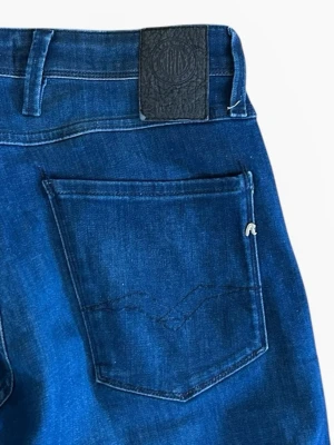  Replay anbass - Snygga blå jeans från Replay med klassisk femficksdesign och raka ben. Jeansen har en mörk tvätt och detaljerad söm på bakfickan samt Replay-logga på bakre läderpatchen. Perfekta för en avslappnad och trendig look.