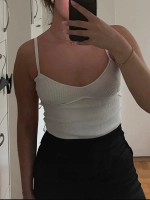 Söt ribbad body - Fin vit stickad body från Gina Tricot, med ribbade dekaner vid bysten.