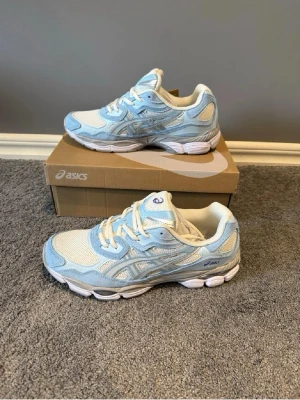 ASICS sneakers i blått och vitt - Snygga sneakers från ASICS i ljusblått och vitt med klassisk siluett. Skorna har meshpaneler för bra ventilation, detaljer i syntet och snörning framtill. Perfekta för dig som gillar sportig stil och vill ha bekväma skor till vardags.