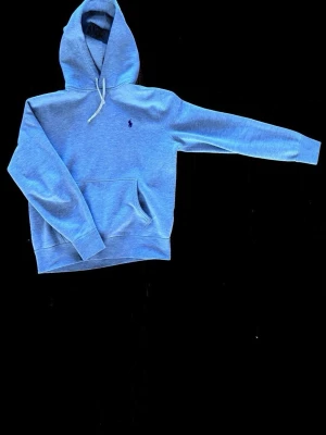 Ljusgrå hoodie från Polo Ralph Lauren - Snygg ljusgrå hoodie från Polo Ralph Lauren med klassisk huva och dragsko. Broderad logga i mörkblått på bröstet och stor magficka framtill. Mjuk bomullsblandning och ribbade muddar vid ärmslut och midja. Perfekt för en chill och stilren look. Nypris 2,4. Köp i en RL butik i USA, självklart äkta!