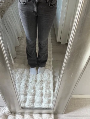 Grå bootcut jeans low waist - Säljer ett par grå bootcut jeans low waist och klassiska fem fickor. Jeansen har en lätt tvättad look och raka ben som går ut lite nedtill. Perfekta till sneakers eller boots och passar till många olika stilar.