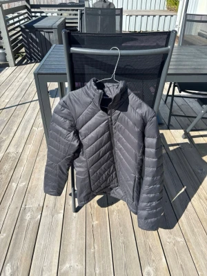 Svart pufferjacka med dragkedja - Snygg svart pufferjacka med hög krage och dragkedja framtill. Jackan har ett stilrent, quiltat mönster och är perfekt för kalla dagar. Materialet är lätt och isolerande, vilket gör den både varm och bekväm att bära.