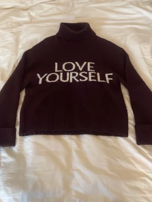 Svart polotröja från Gina Tricot - Cool svart stickad polotröja från Gina Tricot med vit text 'LOVE YOURSELF' framtill. Tröjan har långa ärmar, ribbade muddar och hög krage. Perfekt för dig som vill ha en statement piece i garderoben.mycket bra sick, skriv för fler bilder, pris kan diskuteras!!💗💗