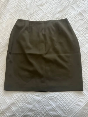 Olivgrön ullkjol från Courtenay 100% ren ull - Snygg olivgrön kortkjol från Courtenay i 100% ren ull. Klassisk rak modell med diskreta sömmar och midjehöjd passform. Perfekt för dig som gillar stilrena och tidlösa plagg.