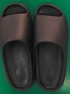 Yeezy slides - Säljer ett par svarta slides-tofflor med öppen tå och chunky sula. Tillverkade i mjukt och flexibelt gummimaterial för extra komfort. Snygg minimalistisk design med räfflad undersida för bättre grepp. Perfekta för chill dagar hemma eller på språng.