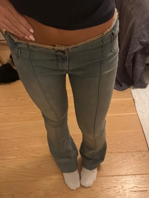 Låga bootcut jeans med rå kant - Super snygga och trendiga bootcut jeans med låg midja. Kanten är fransig och gör jeansen extra snygga och unika. De är i väldigt bra skick och sitter jätte skönt då materialet inte är för stretchigt och inte heller för hårt. Fråga gärna om mått!