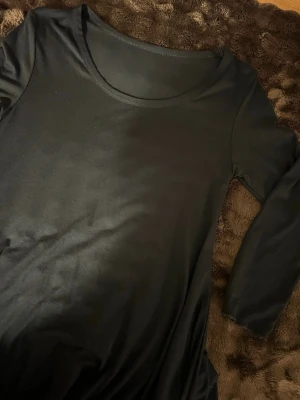 Klänning  - En svart enkel klänning som är bred nertill men små volanger 