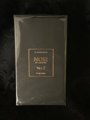 NOIR by Essens No.2 Parfym - NOIR by Essens No.2 är en exklusiv parfym i en elegant svart förpackning med gulddetaljer. Kartongen har en stilren, fyrkantig form och är dekorerad med en stor guldfärgad siffra 4 på toppen. Perfekt för dig som gillar lyxig och mystisk doft.