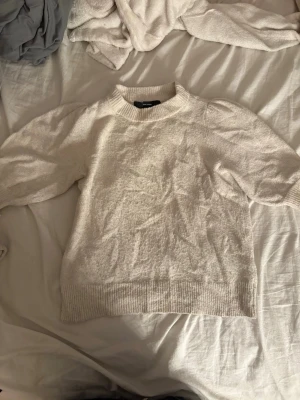 Beige stickad tröja från Vero moda - Mysig beige stickad tröja från vero moda med ballongärmar och ribbade muddar vid hals, ärmslut och nederkant. Tröjan har en avslappnad passform och är perfekt för lager på lager. Materialet känns mjukt och bekvämt.
