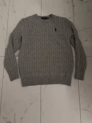 Polo Ralph Lauren Stickad tröja - Grå - Kabelstickad grå tröja från Polo Ralph Lauren. Använd cirka 2-3 gånger nästan helt ny. Storlek M men passar S 