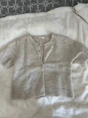 Stickad kortärmad tröja från gina Young  - Jag säljer en beige stickad kortärmad tröja från gina Young. Storlek 158/164. Använd få gånger så i fint skick.