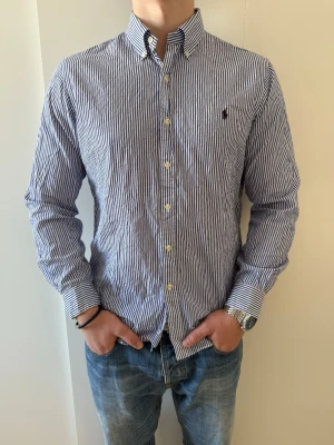 Blårandig skjorta från Ralph Lauren - Klassisk blårandig skjorta från Ralph Lauren. Skjortan är i storlek L och mycket bra skick utan defekter, riktigt bekväm och stilren funkar för både layering eller bara ha som den är