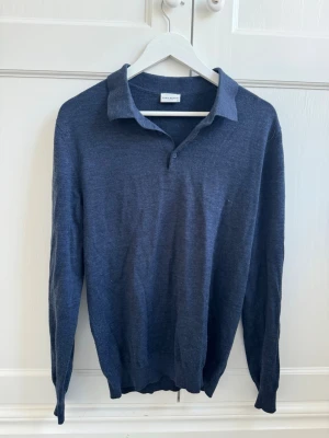 Mörkblå merinoullströja med krage - Klassisk mörkblå långärmad tröja från John Henric i tunn merinoull. Tröjan har en stilren krage med knappar. Perfekt till jeans eller chinos för en clean och enkel stil.