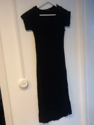 Svart tight klänning från Bik Bok med öppen rygg - En svart lite genom synligt matrial, figurnära klänning med öppen rygg från Bik Bok med korta ärmar och rund halsringning. Klänningen är enkel och stilren, perfekt för dig som gillar minimalistisk stil. Tillverkad i mjukt och stretchigt material för en bekväm passform.