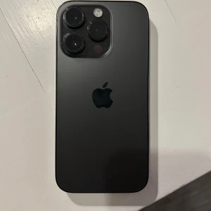 Svart iPhone 14 Pro - Säljer en svart iPhone 14 Pro med stilren design och trippelkamera på baksidan. Telefonen har 86% batteri kapacitet. Inga defekter. Pris kan diskuteras.