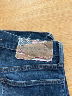 Polo Ralph Lauren Jeans Mörkblå - Säljer ett par Vintage mörkblå Ralph Lauren Denim & Supply slim fit jeans med snygg tvätt och lite sköna slitningar. Jeansen har normal midja och raka ben, perfekta till en avslappnad stil. Bekväm fit. Storlek W31 L34. Pris kan alltid diskuteras ✅.