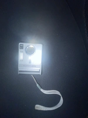 Kodak EasyShare C340 digitalkamera - Säljer en silverfärgad Kodak EasyShare C340 digitalkamera. Kameran har en kompakt, rektangulär design med inbyggd blixt, objektiv och LCD-skärm på baksidan. Praktisk handledsrem i tyg medföljer. Perfekt för dig som gillar retro digitala kameror.