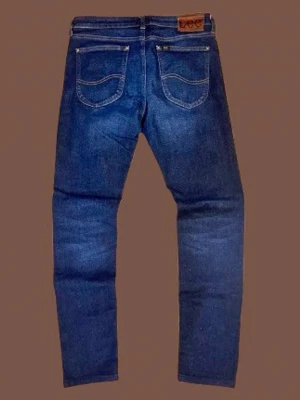  raka jeans från Lee - Säljer ett par klassiska blå jeans från Lee med raka ben och fem fickor. Jeansen har en snygg tvätt och Lee-lapp bak i midjan. Tillverkade i slitstark denim som passar perfekt till vardagslooken.