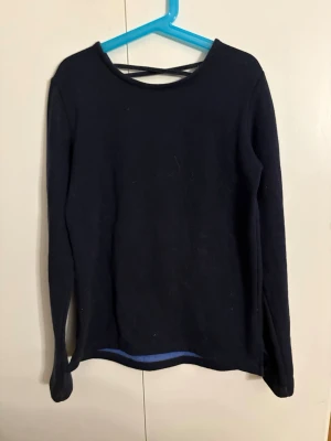 Svart långärmad tröja med snörning - Snygg svart långärmad tröja med rund halsringning fram och dekorativ snörning i ryggen. 