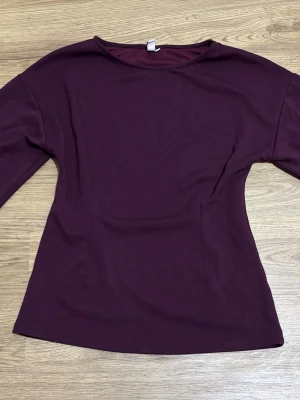 Vinröd långärmad topp med vida ärmar - Snygg vinröd topp med långa, vida ärmar och rund halsringning. Tunn och mjuk i materialet, perfekt att styla till jeans eller kjol. 