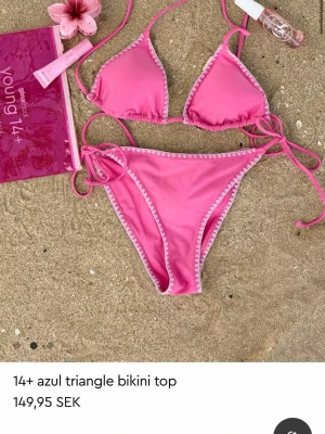Rosa triangelbikini med vita detaljer - Snygg rosa bikini med triangelöverdel och matchande trosa. HELT NY!!💕 Fick när jag fyllde men vi hann inte lämna  tillbaka den inom 14 dar och behöver en större storlek❤️
