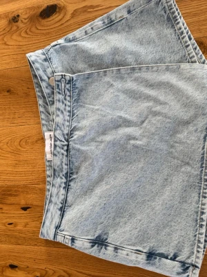 Ljusblå jeansshorts från Calvin Klein - Snygga ljusblå jeansshorts från Calvin Klein Jeans med klassisk femficksdesign och knappstängning. Shortsen har en avslappnad passform och är tillverkade i bomull. Perfekta för varma dagar och enkel att matcha med olika toppar.