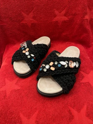 INUIKII "Woven Stones" Sandaler Storlek 39 - Svarta grovt virkade platå sandaler Woven från Inuikii i textil. Trendig platå slip in sandal med vackert virkade öglor och färgade stenar. Sommarens snyggaste sandal, är lika snygg till en sommarklänning som till ett par blåa jeans vilket ger den perfekta balansen mellan bohem och glam. Innersulan är skönt fotformad och mockaklädd vilket ger en bekväm känsla och komfort. Dessa tuffa sandaler vill du inte missa. **** Knappt använd i jättefin kondition. **** Ny pris 2200kr