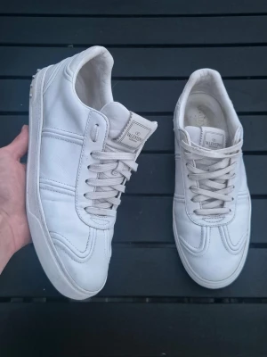 Valentino flycrews - Snygga vita sneakers från Valentino med klassisk låg profil och diskreta nitar på hälen. Skorna har snörning och är tillverkade i skinn för en exklusiv känsla. Perfekta för dig som gillar stilrena och tidlösa sneakers. Endast två nitar borta