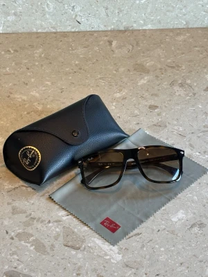 Ray-Ban Boyfriend Two solglasögon - Snygga Ray-Ban Boyfriend Two solglasögon med svart och brun båge i klassisk fyrkantig form. Modellen är RB4547 och kommer med originalfodral och putsduk. Perfekta för dig som vill ha en cool och tidlös look. Skriv vid frågor!