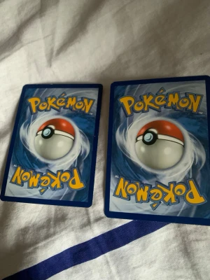 Pokémon energikort, Fighting & Lightning - Två Pokémon energikort: ett Fighting Energy i rödbrun färg och ett Lightning Energy i gul färg. Perfekta för att komplettera din samling eller använda i Pokémon TCG-spel. Klassisk design med Pokéball på baksidan.