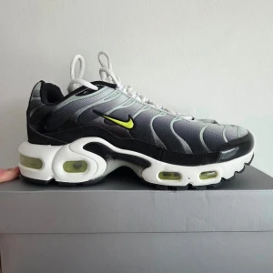 Nike Air Max Plus TN Bright Cactus  - Nike Air Max Plus sneakers i grått och svart med vita detaljer och neongul Swoosh. Ovandelen är i mesh med vågiga linjer och synliga Air-enheter i sulan. Klassisk siluett med vita skosnören och svart innersula med neongula detaljer. Oanvänt sneakers. Kartongen saknas.