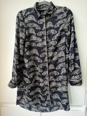Mörkblå skjorta med leopardmönster Lindex - Snygg mörkblå skjorta från Lindex med coolt leopardmönster i vitt. Skjortan har lång ärm, klassisk krage och knäppning framtill. Lika snygg knäppt som ledig öppen. 