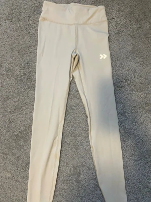 Beige träningstights från Hummel - Snygga beige träningstights från lager 157. Perfekta för gymmet eller löprundan. Endast använda 1 gång och i mycket bra skick! Tveka inte att höra av dig vid frågor.💕
