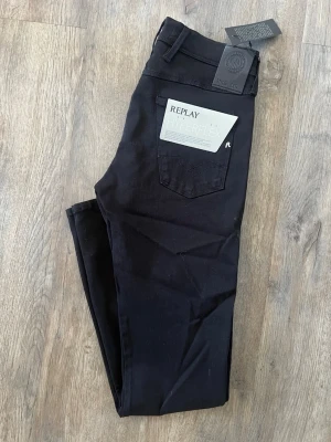 Replay Anbass Hyperflex jeans - Strlk: 30/32.   Snygga svarta jeans från Replay med Hyperflex-teknologi som ger extra stretch och komfort. Modellen har klassisk femficksdesign, smal passform och normal midja. Perfekta för dig som vill ha stilrena och bekväma jeans med modern look. Helt oanvända!