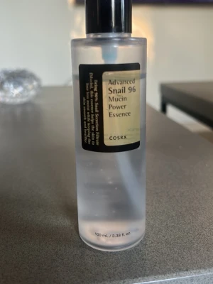 COSRX Snail 96 Mucin Power Essence - COSRX Advanced Snail 96 Mucin Power Essence är en genomskinlig ansiktsessens i plastflaska med pump. Innehåller 100 ml och har en lätt, gel-liknande konsistens. Essensen är känd för att återfukta och stärka huden med snigelsekretfiltrat.