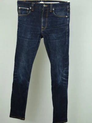 Nudie Dry true selvage  - NUDIE DRY TRUE SELVAGE JEANS Storlek : 29/32 Modell : Lean Dean Mått : A = 38CM - B = 98CM - C = 14,5CM Användning : Jeansen är i ett fint skick utan defekter Nypris : Cirka 2700SEK Modellen på bilden : 182CM och väger 73,5KG