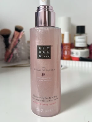 Rosa body spray Rituals Sakura - Shimmering body spray från Rituals, The Ritual of Sakura. Flaskan är rosa med skimrande effekt och har en pump. Doft av rice milk och cherry blossom. Perfekt för dig som vill ha en fräsch och glittrande känsla, Korken är borttappad. 