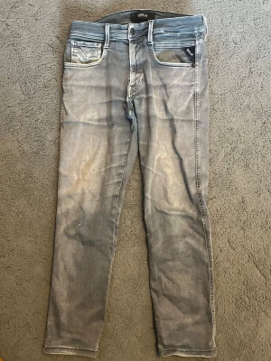 Grå slim fit jeans från Replay - Säljer ett par grå jeans från Replay i modell anbass. Har en liten tråd som sticker ut vid ena knäskålen (kolla första bilden)