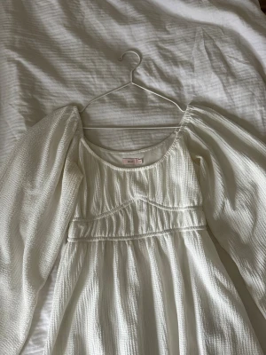 Vit långärmad klänning från Nelly - Säljer en vit klänning från Nelly i storlek XS. Klänningen har lång puffärm, rund halsringning och ett strukturerat tyg i bomull.Inga defekter, använd fåtal gånger.