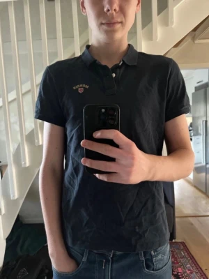 Morris piké  - Klassisk mörkblå pikétröja från Morris med korta ärmar och krage. Tröjan har en liten broderad logga på bröstet och är tillverkad i mjuk bomull. Perfekt till jeans eller shorts för en avslappnad stil. Pikén är i storlek M. Hör av er vid funderingar!